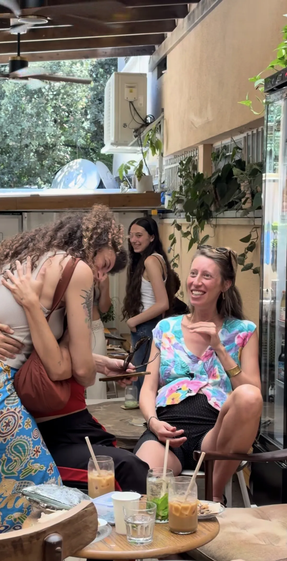 חברים צוחקים ומתחבקים בחצר של בית הקפה